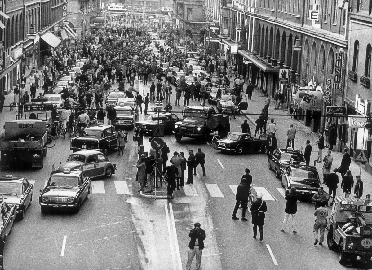 Black and white photo of a crowded Stockholm street with cars, taxis and trucks crossing between lanes
